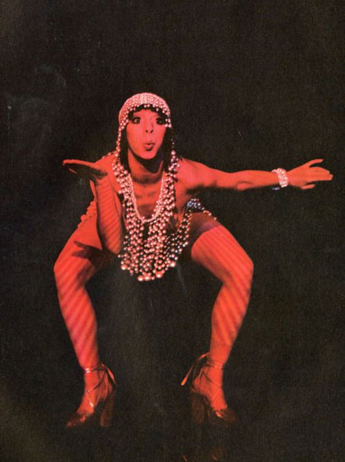 Cabaret performer in a beaded headdress under red light